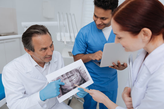 Attentive woman pointing on picture with teeth