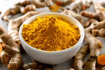 Papier Peint photo Herbes Turmeric powder and turmeric capsules on wooden background