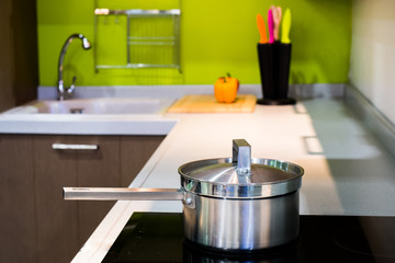 green modern kitchen  and stainless steel pot on induction electric hob