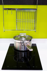 green modern kitchen  and stainless steel pot on induction electric hob