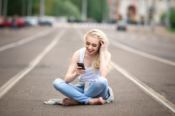 Beautiful girl is sitting on the road and talking on the phone