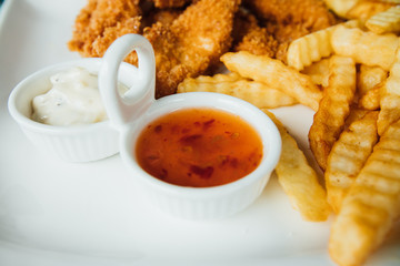 French fries, chicken nuggets and sauces on a white plate