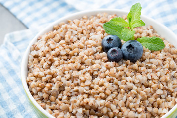 Buckwheat porridge in a bowl with mint leaves and blueberries.