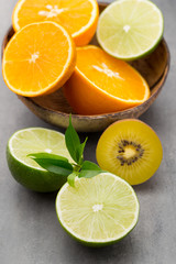 Obraz na płótnie Canvas Mixed citrus fruit lemons, orange, kiwi, limes on a gray background.