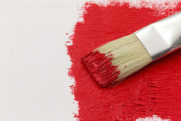 Wet red paint with a brush on an artist canvas.