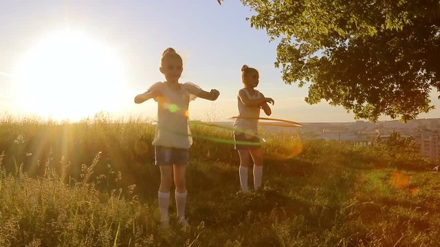 Two kids girls play with hula-hoop