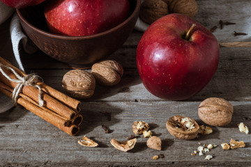 fresh red apples, cinnamon sticks and walnuts on rustic wooden tabletop