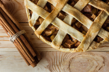 Fototapeta na wymiar top view of homemade apple pie and cinnamon sticks on rustic wooden tabletop