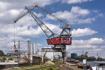 Fototapeta na wymiar Red old harbor crane on rails at Rhine river