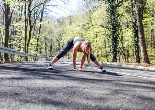 Young sports woman stretching his muscles before running on the road.