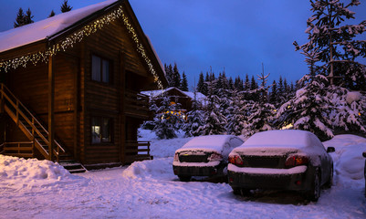 A fairy-tale house in the woods amid the snow-covered fir trees, Christmas landscape. Winter nature.