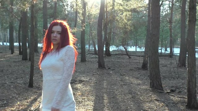 Woman dances in the sun, she is in the forest.