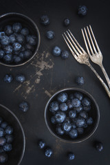 Schüsseln mit Blaubeeren zusammen mit zwei Gabeln auf einem alten rostigen Untergrund