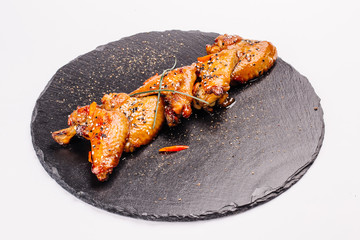 Grilled chicken wings on a black stone plate .