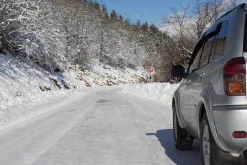 SUV car on snow covered mountain road. Car tires on winter road covered with snow