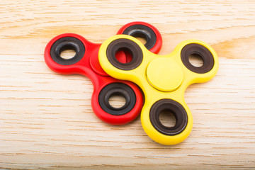 Yellow and red fidget finger spinner stress anxiety relief toy isolated on wooden background.