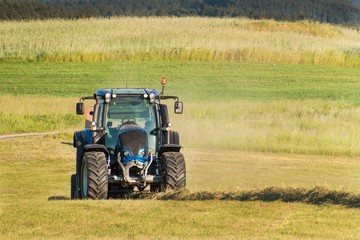 Fototapeta premium Blue tractor on the pasture.. Agricultural work on the farm in the Czech Republic.