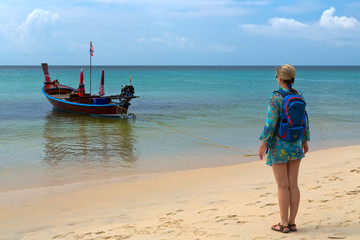 girl with a backpack on the beach, traditional Thai boat