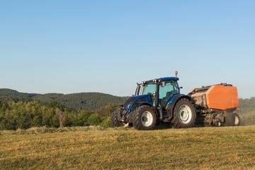 Blue tractor on the pasture.. Agricultural work on the farm in the Czech Republic.