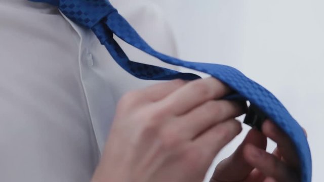 A man ties up a tie with a raised collar, a close-up