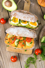Sandwiches with avocado, eggs and tomato on a wooden background. Fresh organic vegetables, eggs and whole wheat bread. Healthy breakfast. Retro style.