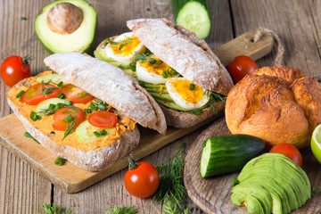 Sandwiches with avocado, eggs and tomato on a wooden background. Fresh organic vegetables, eggs and whole wheat bread. Healthy breakfast. Retro style.