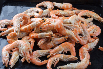 A lot of shrimp on a black background. Good selection of raw shrimps for dinner on stone plate. Food background.