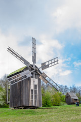 Fototapeta na wymiar Ancient traditional wooden windmill, beautiful spring landscape with sky. National architecture. National Museum Pirogovo in the outdoors near Kiev.