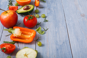 Border of fresh vegetables on blue wood background with copy space