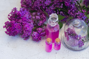Obraz na płótnie Canvas Lilac essence in glass vials and rwig with fresh lilac flowers