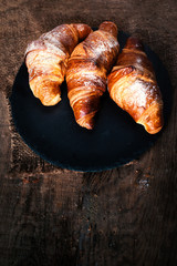 Fresh croissants on a table close up. Tasty golden croissants on dark brown  wooden background macro