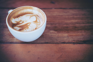 Top view image of hot latte coffee with latte art on vintage wooden table