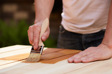 Man hand with paintbrush painting on a wooden table