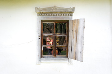 National Museum Pirogovo in the outdoors near Kiev. An old antique window with flowers in a vintage peasant white house in Ukraine. An antique wooden window frame with a door.