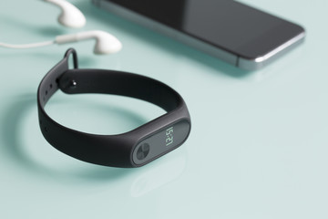Fitness tracker, smartphone and earphones on green glass background.