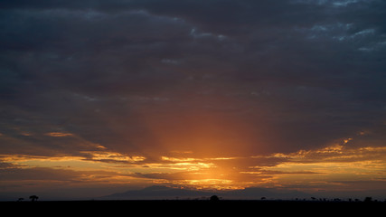 Sun rising through rain clouds in Serengeti, Tanzania