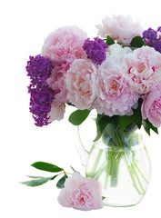 Fresh peony and lilac flowers buds colored in shades of pink in vase close up isolated on white background