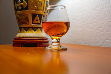 Transparent glass with cognac and lemon in the light of an antique vintage lamp
