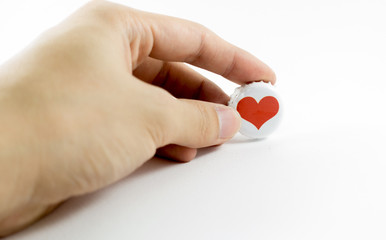 Hand holding red heart on white lid isolated