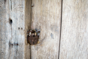Natural material. Old metal rusty padlock, bolt on a wooden door. Old wooden brown background close-up.