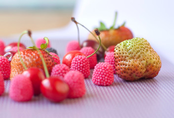 A group of strawberries, cherries and candies raspberry isolated  on the violet background