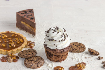 Confectionery basket with caramel and nuts, capcake with creamy cream, biscuits and caramel