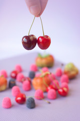Girl hand holding cherry on the blurred colored background