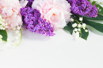 Floral borders of fresh flowers - lilac, peonies and lilly of the walley flowers and leaves on white background