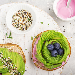 Healthy burgers for snacks, for breakfast with a rose from avocado and blueberries with sesame seeds and strawberry sauce on a light background. Top view. The concept of healthy eating right