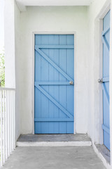 Blue wooden door at the end of hall way