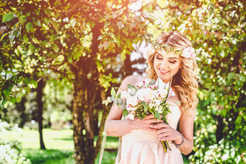 Fototapeta premium Young bride with wedding bouquet outdoor in the park