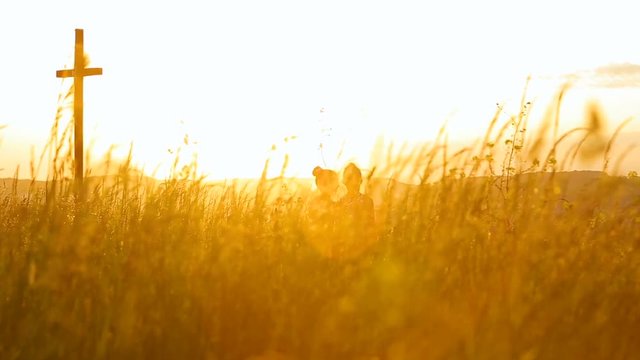 Two sisters walking in a field during sunset holding gands