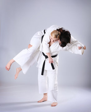 Young sporty women practicing martial arts on light background