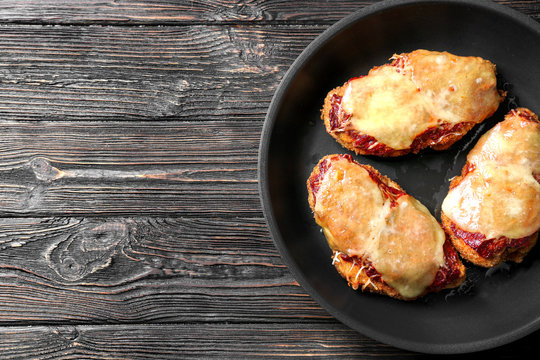 Tasty chicken parmesan with cheese on frying pan, top view